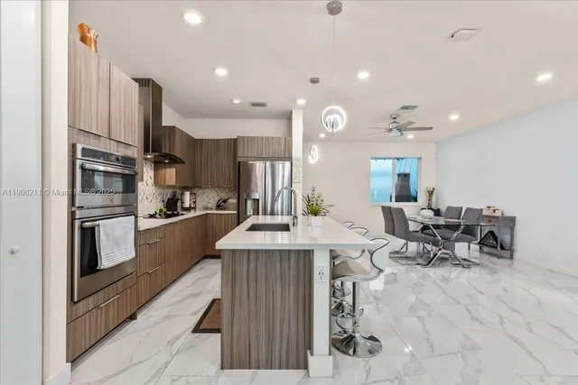 a large kitchen with kitchen island a large counter top stainless steel appliances and cabinets