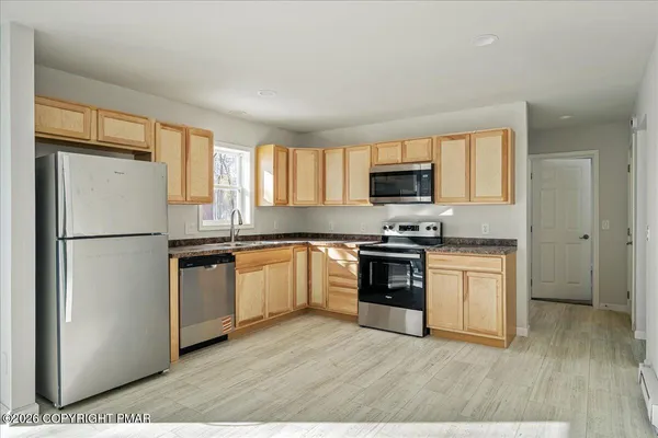 a kitchen with granite countertop a refrigerator stove top oven and sink