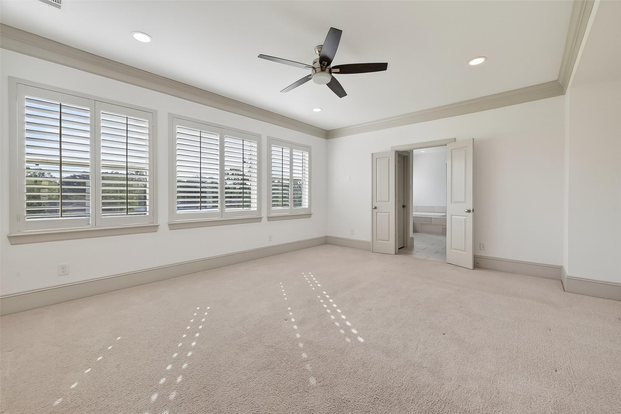 10514 Concha Lane Houston, TX 77096 - Photo 16 of 50 Generous sized primary suite with plenty of room for your King sized furniture. Wall of windows with plantation shutters overlooking back green space. No neighbors behind. Recessed lights, ceiling fan, and crown molding.