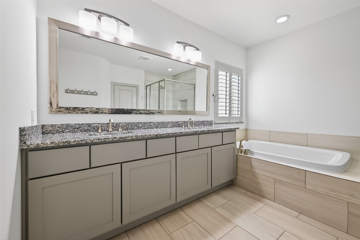 10514 Concha Lane Houston, TX 77096 - Photo 18 of 50 Primary bathroom has dual sinks and lots of storage cabinets. Large soaking tub with planation shutters for privacy.