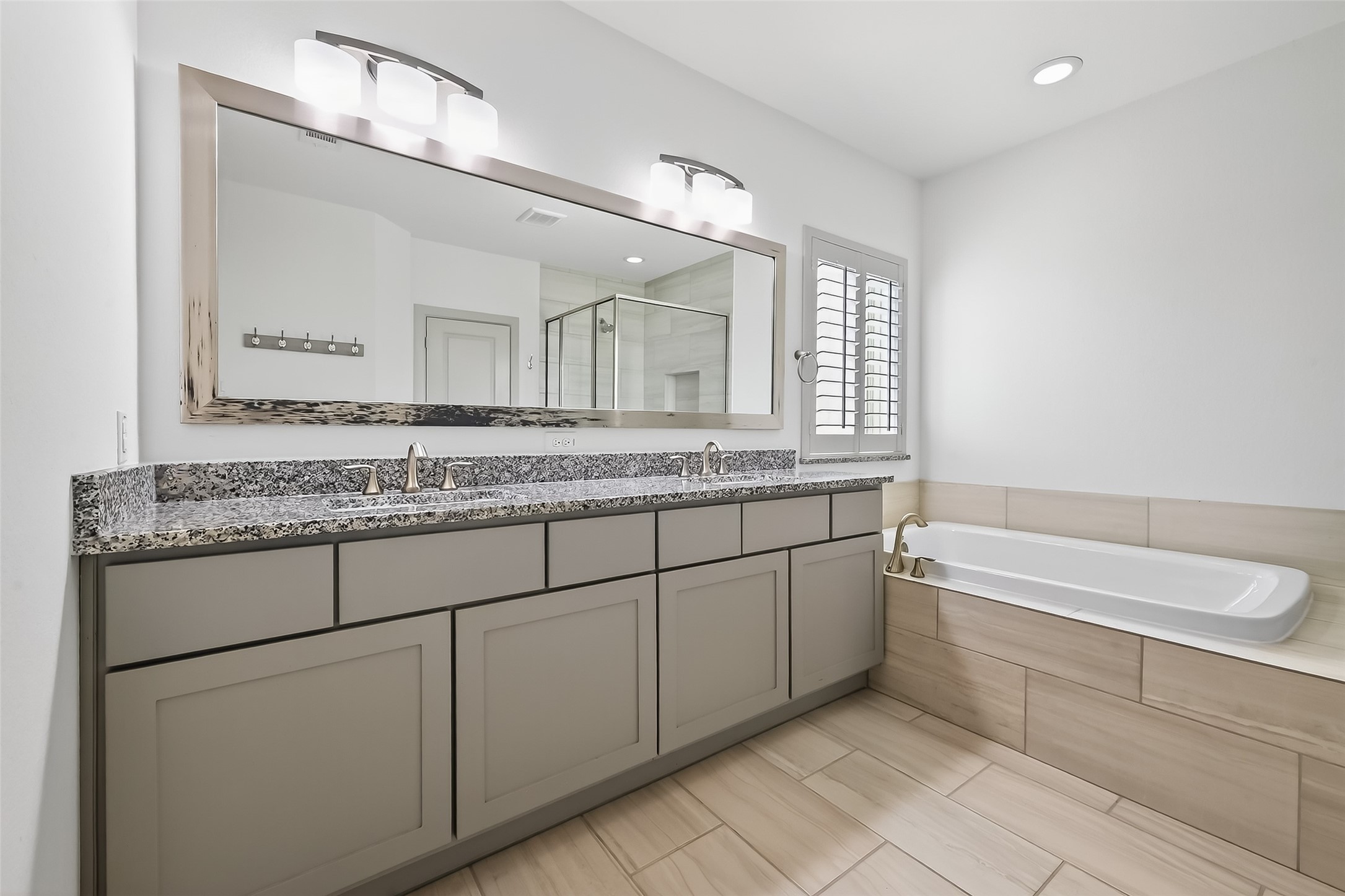 10514 Concha Lane Houston, TX 77096 - Photo 18 of 50 Primary bathroom has dual sinks and lots of storage cabinets. Large soaking tub with planation shutters for privacy.