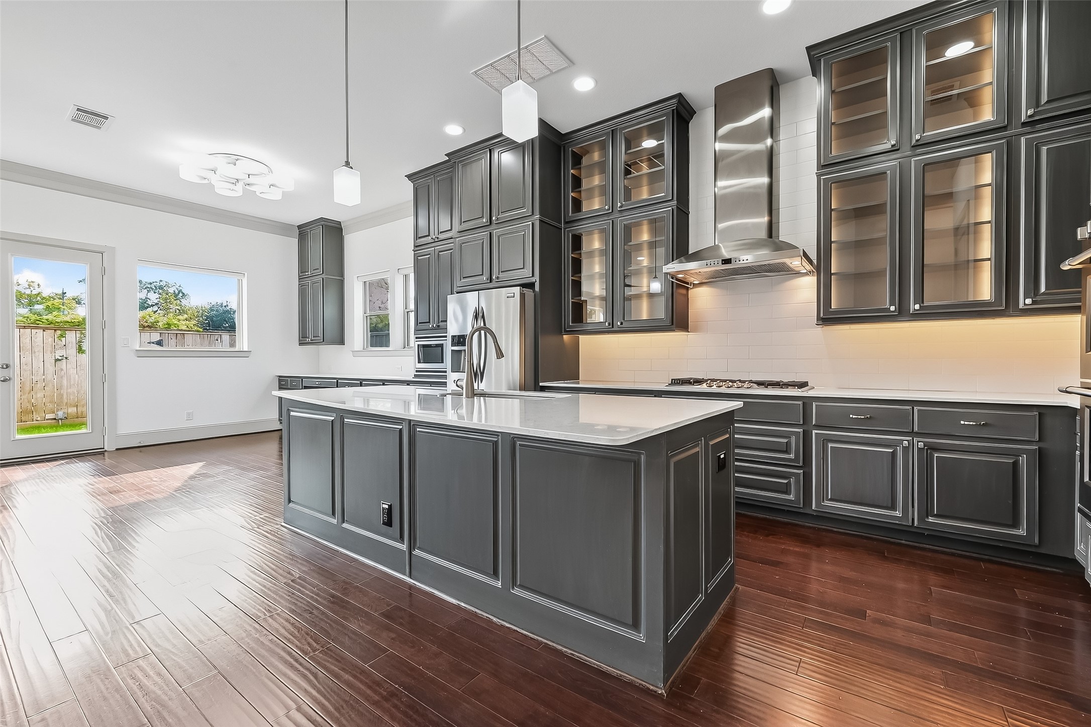 10514 Concha Lane Houston, TX 77096 - Photo 4 of 50 Gourmet island kitchen with with cool overhead pendants lights. Glass front cabinets go all the way to the ceiling and are lit from within for a dramatic effect. Plenty of overhead recessed light and under-cabinet lights for task work or cool ambiance.