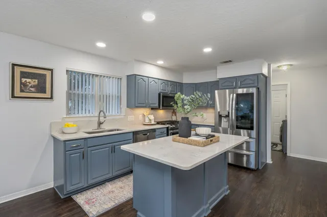 a kitchen with a stove a sink dishwasher a kitchen island with wooden cabinets and floor