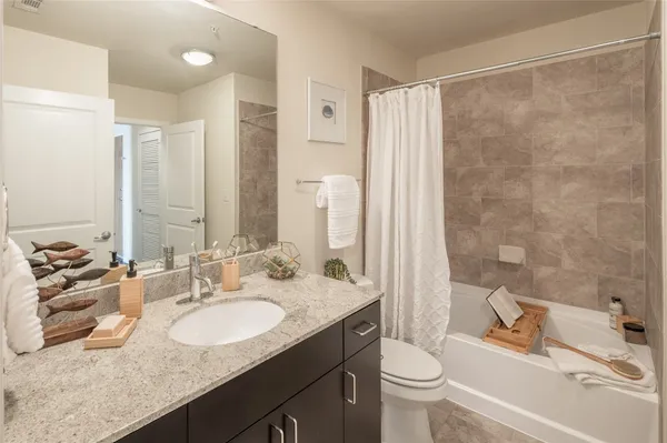 a bathroom with a granite countertop sink a toilet a mirror and shower