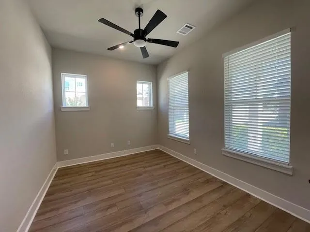 an empty room with wooden floor and windows