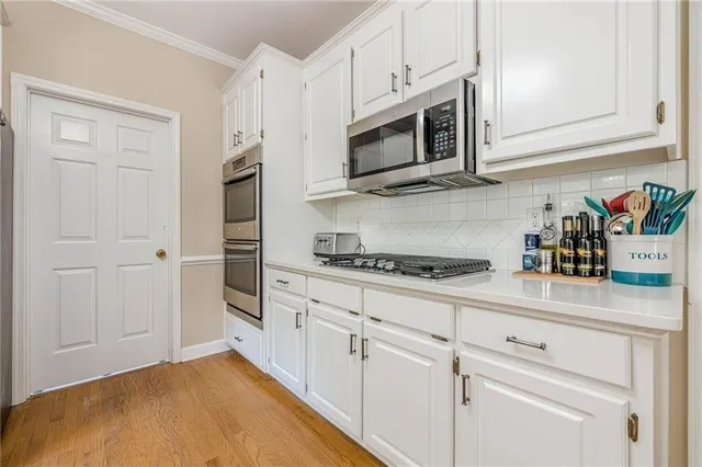 a kitchen with stainless steel appliances granite countertop white cabinets and a stove a oven with white countertops