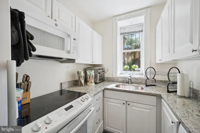 a kitchen with granite countertop a sink stainless steel appliances and cabinets