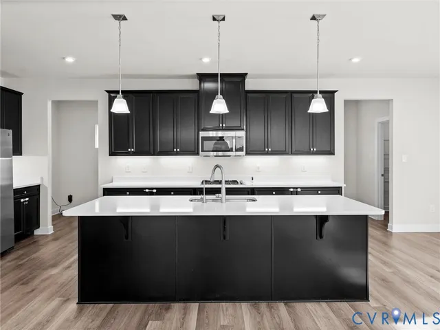 a kitchen with kitchen island granite countertop a sink a counter space appliances and cabinets