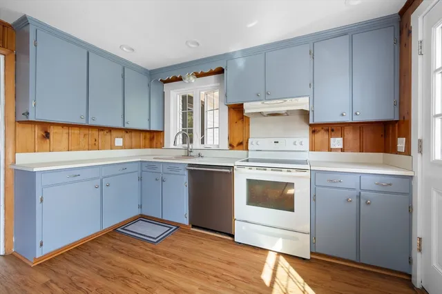 a kitchen with cabinets appliances and wooden floor