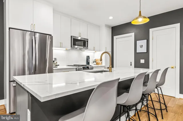 a kitchen with stainless steel appliances granite countertop a table chairs in it and wooden floors