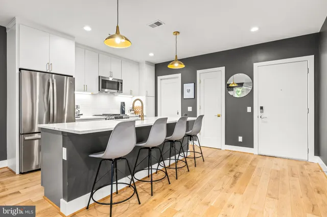 a kitchen with stainless steel appliances granite countertop a refrigerator a stove a sink dishwasher a dining table and chairs with wooden floor
