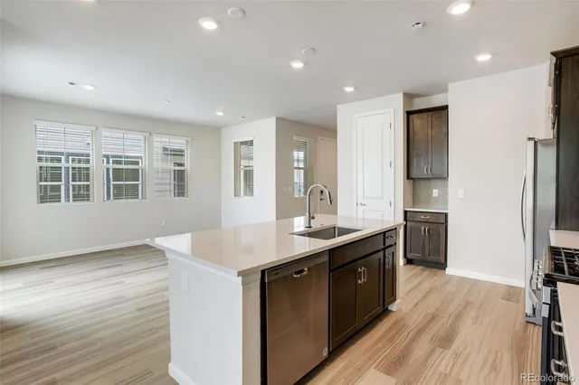 a kitchen with stainless steel appliances granite countertop white cabinets a refrigerator a sink a stove a microwave and wooden floors