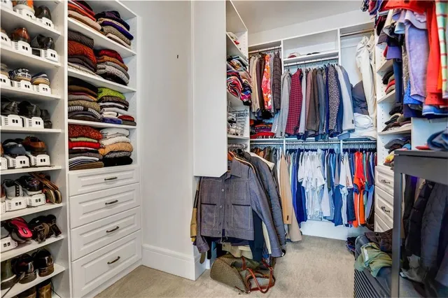 a view of walk in closet with clothes and shoes