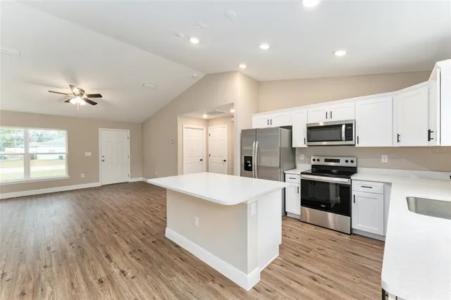 a large kitchen with stainless steel appliances granite countertop a lot of counter space and wooden floor