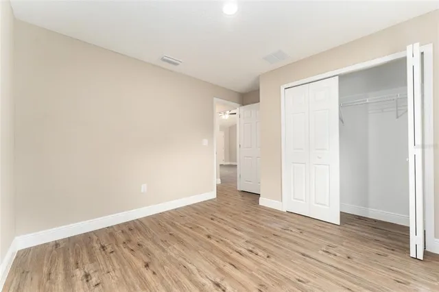 a view of an empty room with wooden floor and closet