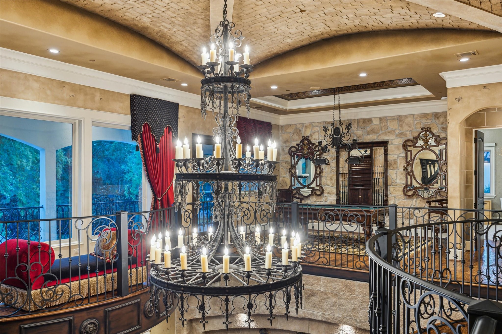 11095 Memorial Drive Houston, TX 77024 - Photo 21 of 48 The family room boasts a 26-ft ceiling with a Noce stone inlay and wood trim centered around a 3-tier forged iron chandelier. Dual Juliet balconies with ornate iron railings overlook the space, while stone accents and rich wood details create a timeless charm. A true architectural masterpiece, perfect for refined living and entertaining.