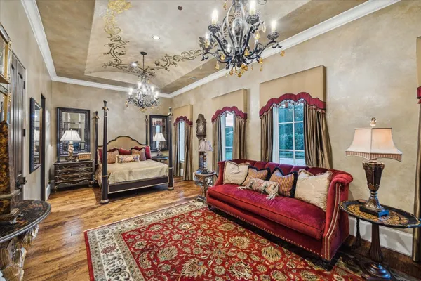 a spacious bedroom with a bed a couch and chandelier