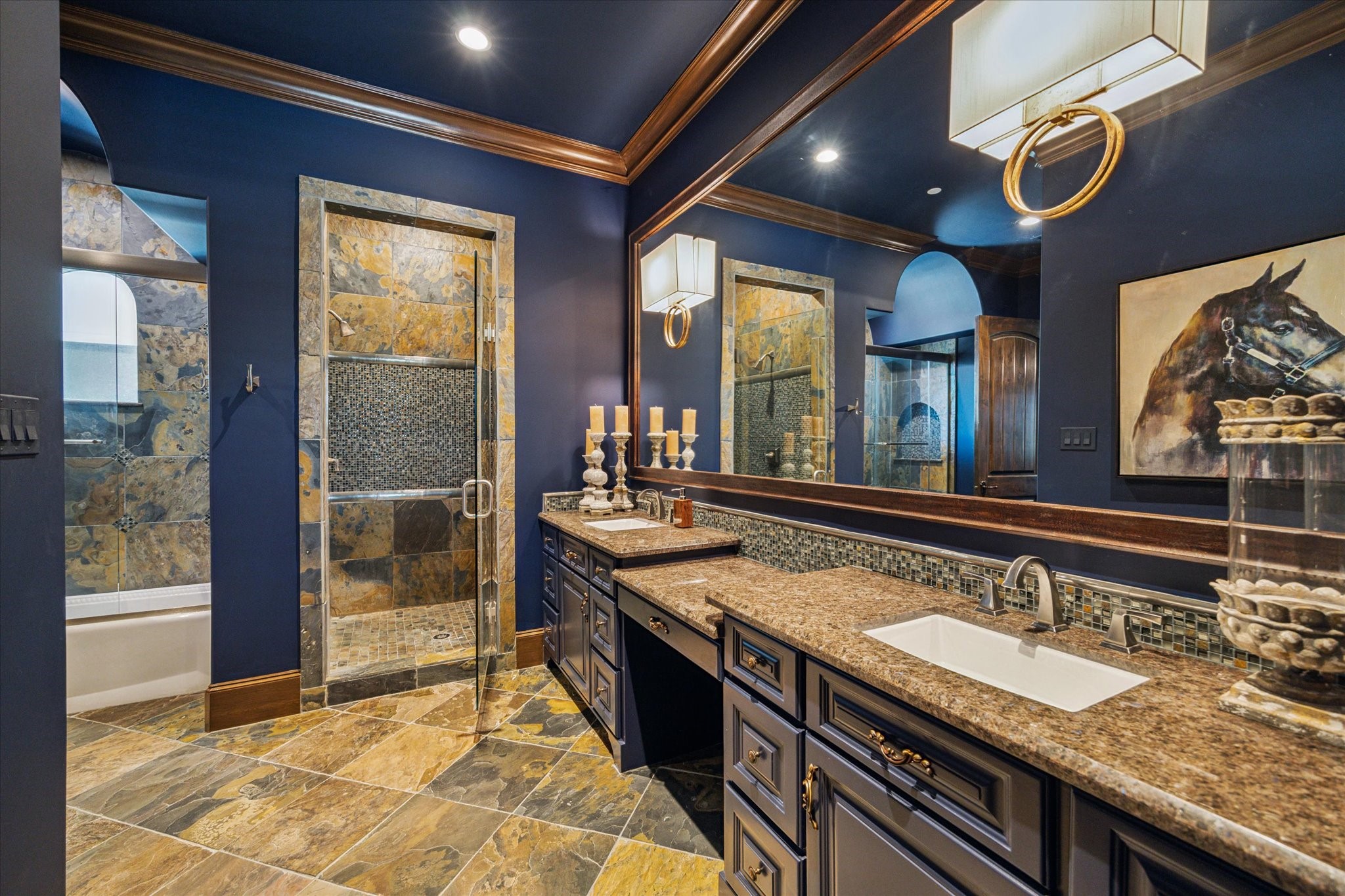 11095 Memorial Drive Houston, TX 77024 - Photo 35 of 48 The en-suite bathroom continues the sophisticated theme with matching blue-painted walls and ceiling, complemented by slate tile flooring and accent walls. The navy double vanity features a sitting area, Labrador Antico granite countertops, and double porcelain undermount sinks.