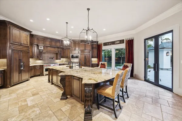 a large kitchen with granite countertop a large stove a sink dishwasher a dining table and chairs with wooden floor