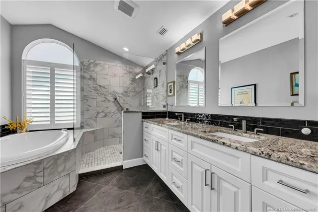 a bathroom with a granite countertop double vanity sink a mirror and a bathtub