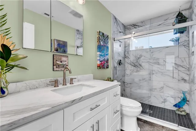 a bathroom with a granite countertop sink toilet and shower