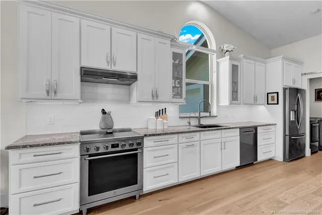 a kitchen with stainless steel appliances granite countertop a sink cabinets and a wooden floor