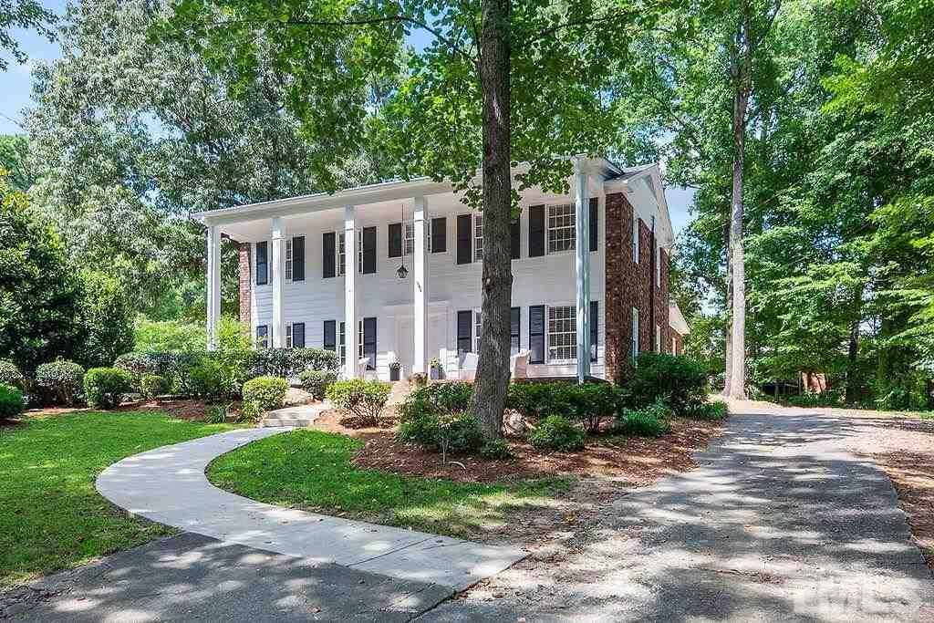 a front view of a house with a yard and trees