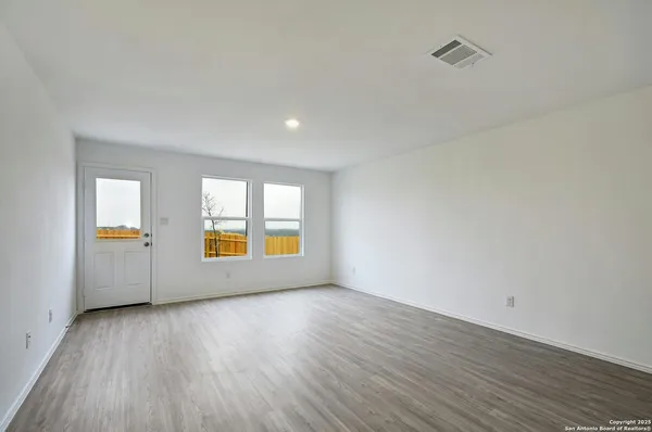 an empty room with a window and wooden floor