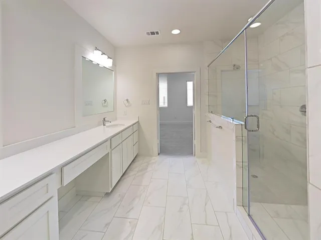 a bathroom with a double vanity sink a toilet and shower
