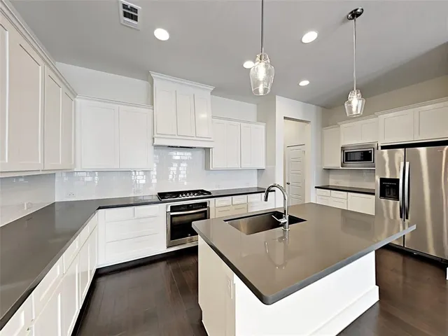 a kitchen with stainless steel appliances granite countertop a sink a stove and refrigerator