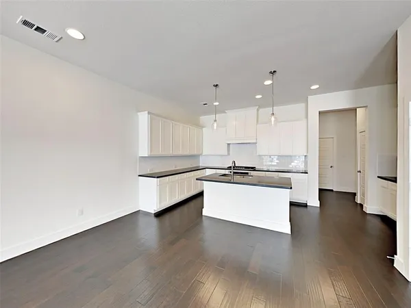 a large white kitchen with a white countertops a stove and a wooden floor