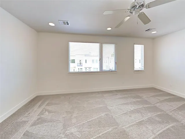 an empty room with windows and ceiling fan