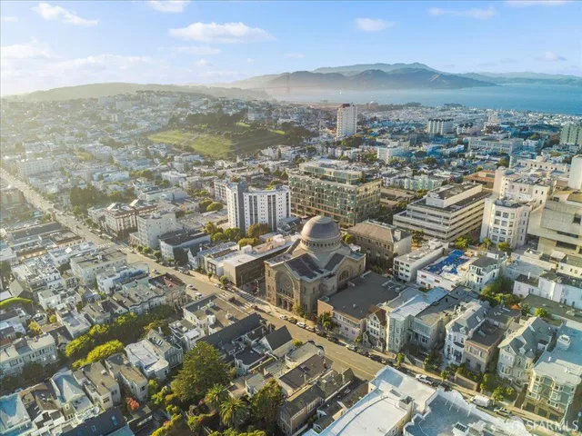 a front view of a building with lot of cars and trees