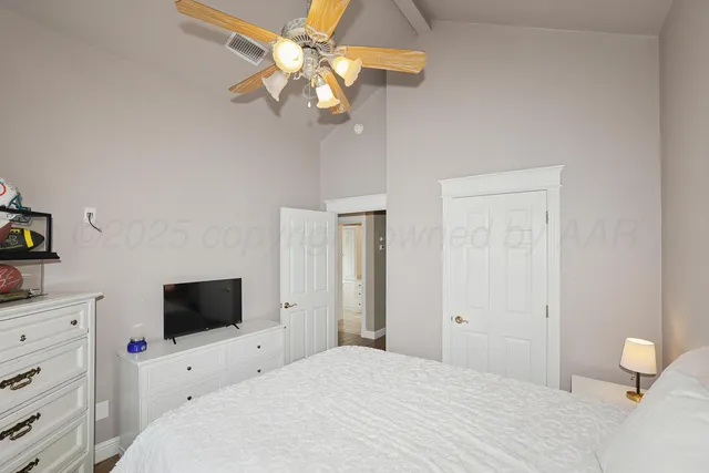 a bedroom with a bed a flat screen tv and a chandelier