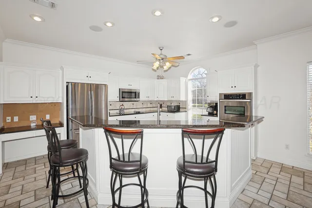 a kitchen with stainless steel appliances granite countertop a kitchen island a stove a table and chairs