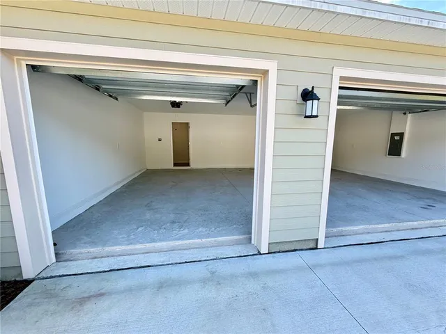 an empty room with a chandelier fan and windows