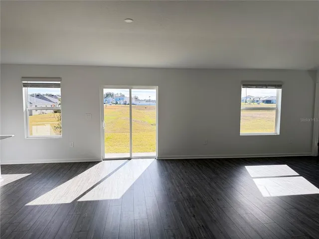 a view of a kitchen with a fridge wooden floor and a window
