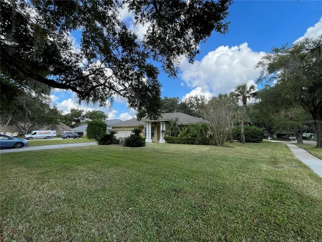 a view of a house with a big yard and large trees