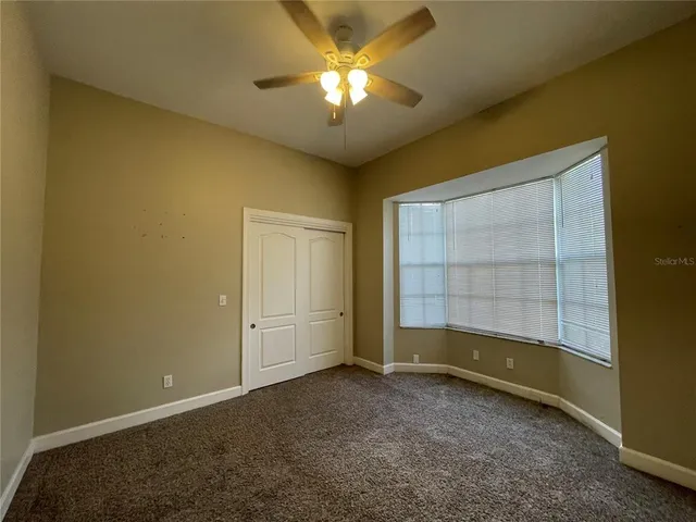 an empty room with a chandelier fan and windows