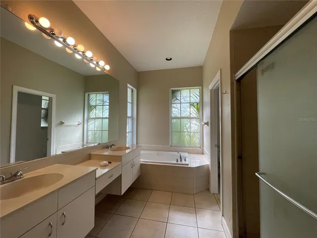 a spacious bathroom with a tub sink shower and mirror