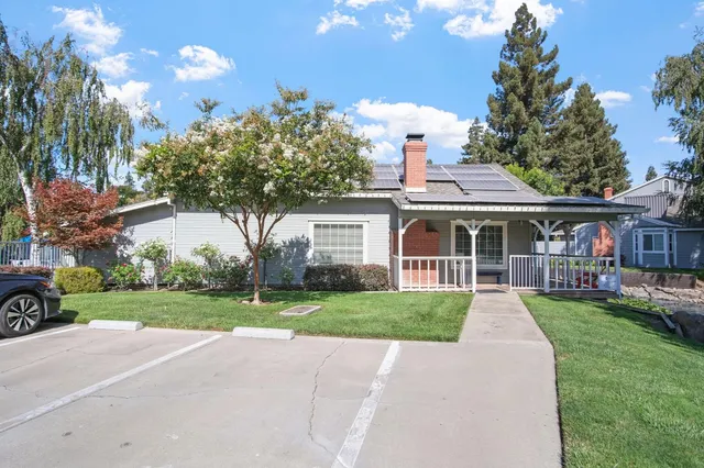 a front view of a house with a yard and potted plants