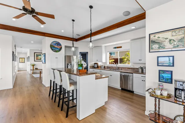 a kitchen with a dining table chairs stove and white cabinets with wooden floor