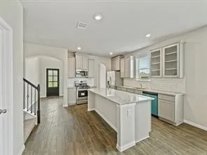 a large kitchen with cabinets wooden floor and stainless steel appliances