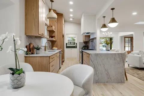 a kitchen with stainless steel appliances a dining table a sink cabinets and wooden floor