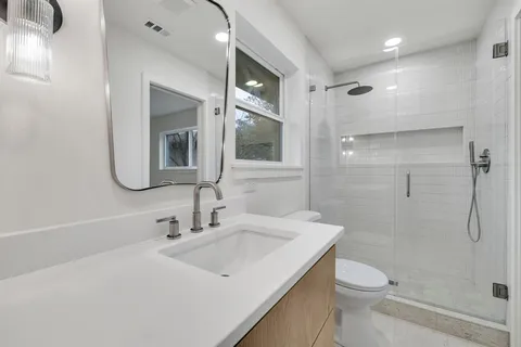 a bathroom with a sink a toilet and shower