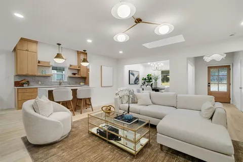 a living room with furniture kitchen view and a chandelier