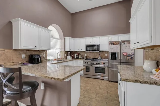 a kitchen with kitchen island granite countertop a stove sink and cabinets