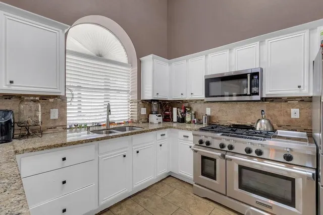 a kitchen with stainless steel appliances granite countertop white cabinets a sink and dishwasher