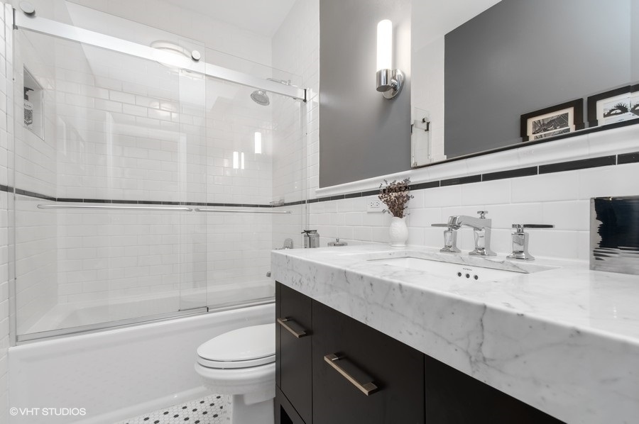 550 West Surf Street, Unit C314 Chicago, IL 60657 - Photo 17 of 21 a bathroom with a granite countertop sink a toilet a mirror a vanity and shower