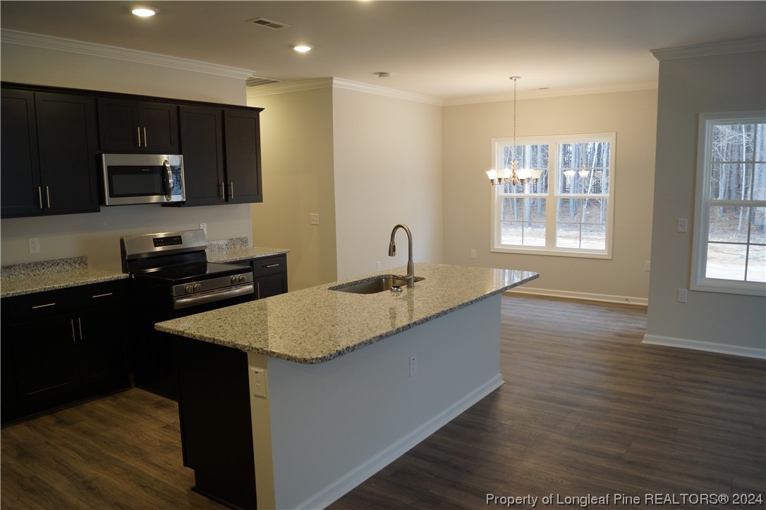 111 Knotts Berry Road Bunnlevel, NC 28323 - Photo 11 of 32 a kitchen with stainless steel appliances granite countertop a sink a stove a microwave and wooden cabinets
